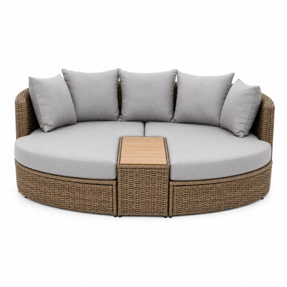 Okrągła sofa z technorattanu z szarymi poduszkami i drewnianym stolikiem